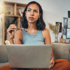 woman pondering a though while working on the computer